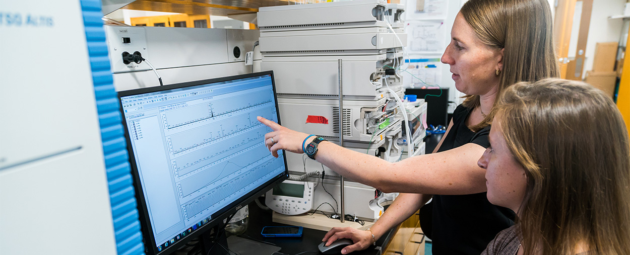 Assistant Professor of Ocean Sciences Kimberly Popendorf and graduate assistant Kaycie Lanpher review data from a liquid chromatography triple quadruple mass spectrometer used for toxin analysis.
